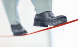 Unstable job - Low section of a business person walking on thin red line