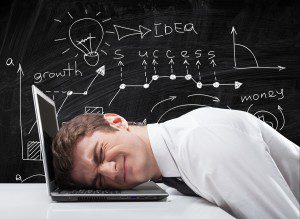 Stress. Young businessman with his head squeezed between a laptop keyboard and a rock